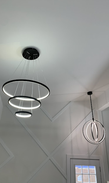 Modern black three-ring chandelier and orbital pendant in Calgary entryway