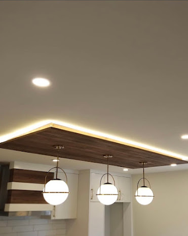 Custom recessed wood-panel ceiling with LED perimeter and globe pendant trio